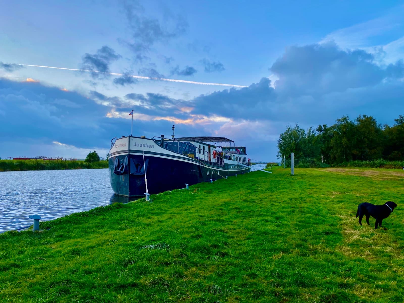 Ship sailing along a Dutch waterway at sunset with green polders